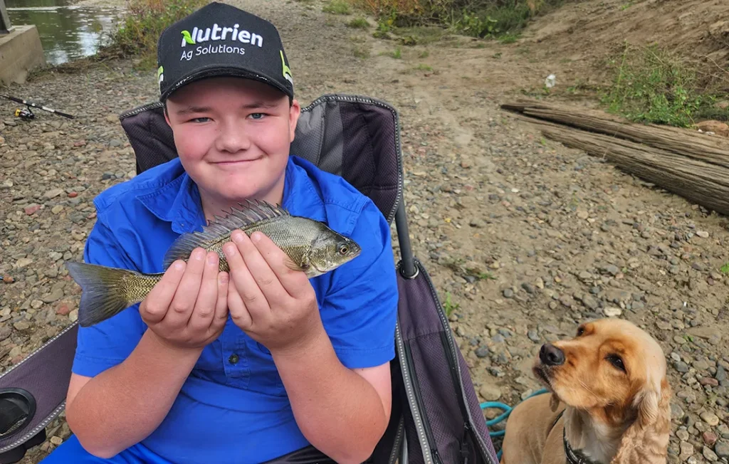 Young boy proudly holding a fish he caught during an outdoor activity with JKL Support Services in Forster NSW and surrounding areas.